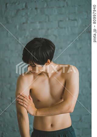 腕の筋肉を触る男性 80997940