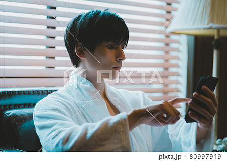 バスローブ姿でスマホを操作する若い男性 バスローブ姿でスマホを操作する若い男性 80997949