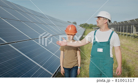 Engineer father is explaining to his little son an operation and performance of photovoltaic solar panels. Father and son happy Family concept. Boy and his dad engineer architect with safety helmets Engineer father is explaining to his little son an operation and performance of photovoltaic solar panels. Father and son happy Family concept. Boy and his dad engineer architect with safety helmets 81001317