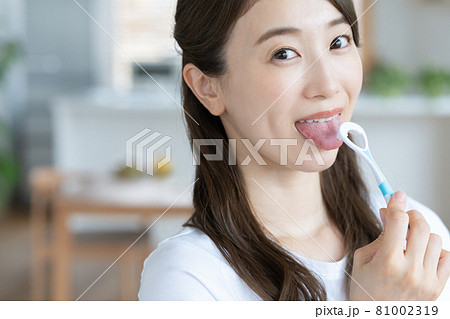 自宅のリビングで舌磨きをする若い女性 81002319