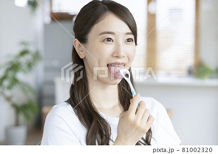 自宅のリビングで舌磨きをする若い女性 81002320