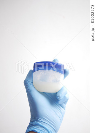hand in latex gloves holding petroleum jelly on white background  81002578