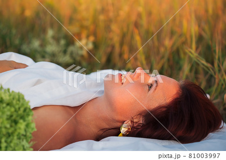 Charming woman in a field with a bouquet of hydrangea in a white men's shirt 81003997