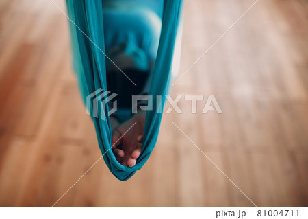 Woman doing aerial yoga in studio. Female practicing air yoga in hammock Woman doing aerial yoga in studio. Female practicing air yoga in hammock 81004711