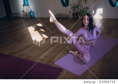 Woman doing aerial yoga in studio. Female practicing air yoga in hammock Woman doing aerial yoga in studio. Female practicing air yoga in hammock 81004714