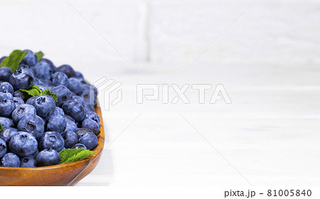 Blueberries With a Green Mint leaf in a Wooden Bowl on a white top view, Summer Freshly Berry, Copyspace 81005840