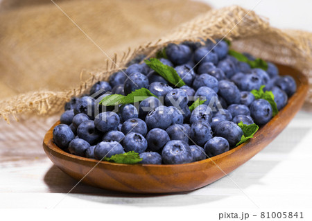 Blueberries With a Green Mint leaf in a Wooden Bowl on a white with piece of cloth top view, Summer Freshly Berry, Copyspace 81005841