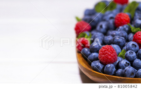 Blueberry and Raspberry With a Green Mint leaf in a Wooden Bowl on a white top view, Summer Freshly Berry, Copyspace Blueberry and Raspberry With a Green Mint leaf in a Wooden Bowl on a white top view, Summer Freshly Berry, Copyspace 81005842