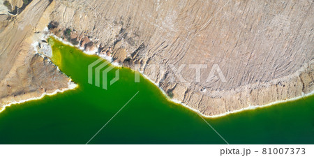 Shore of toxic green lake in abandoned open pit copper mine. Aerial panorama from directly above 81007373