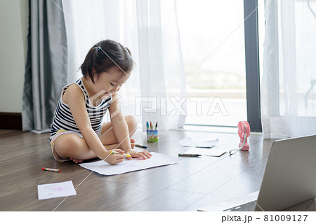 Asian little girl with a crayon drawing on the paper Asian little girl with a crayon drawing on the paper 81009127