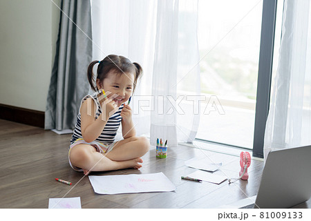 Asian little girl with a crayon drawing on the paper Asian little girl with a crayon drawing on the paper 81009133