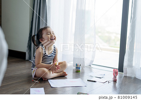 Asian little girl with a crayon drawing on the paper 81009145