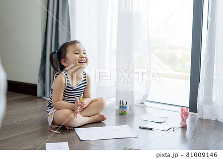 Asian little girl with a crayon drawing on the paper 81009146