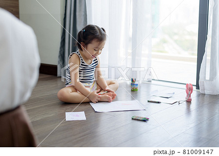 Asian little girl with a crayon drawing on the paper 81009147