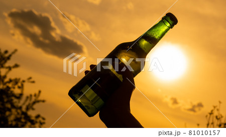 Woman holding bottle of beer outdoors against sky background. Woman holding bottle of beer outdoors against sky background. 81010157