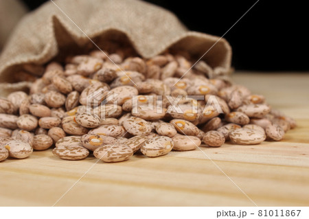 Burlap Bag of Dried Pinto Beans Spilled on Wooden Table Burlap Bag of Dried Pinto Beans Spilled on Wooden Table 81011867