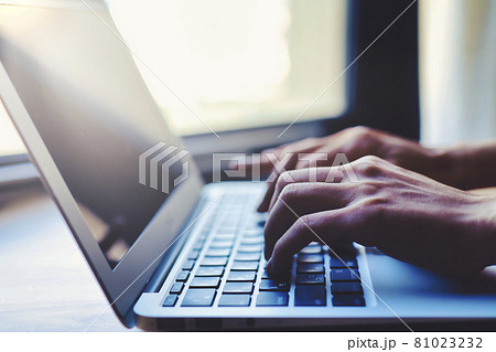 窓際でラップトップを使用する人物の手元クローズアップ 背景ぼかし 81023232