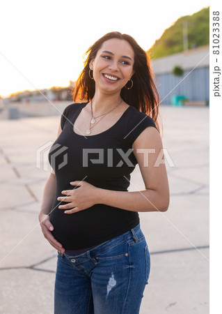 Portrait of hispanic pregnant woman walking on embankment at sunset. Pregnancy and motherhood concept. Portrait of hispanic pregnant woman walking on embankment at sunset. Pregnancy and motherhood concept. 81023388