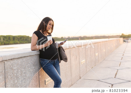 Pregnant woman with smartphone at park. Pregnancy, technology and communication concept. Space for text Pregnant woman with smartphone at park. Pregnancy, technology and communication concept. Space for text 81023394