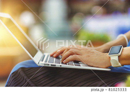 屋外でラップトップを使用する人物の手元クローズアップ 緑背景ぼかし 81025333
