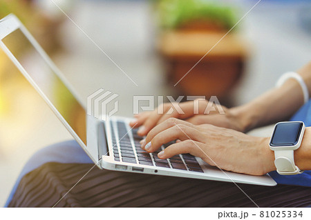 屋外でラップトップを使用する人物の手元クローズアップ 緑背景ぼかし 81025334