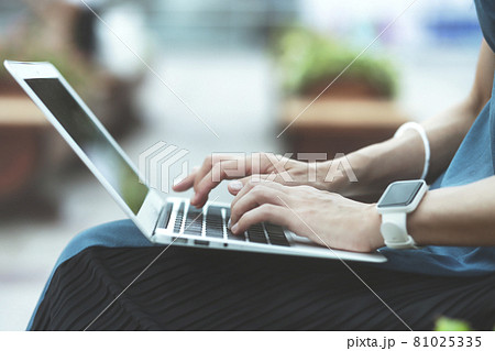 屋外でラップトップを使用する人物の手元クローズアップ 緑背景ぼかし 81025335