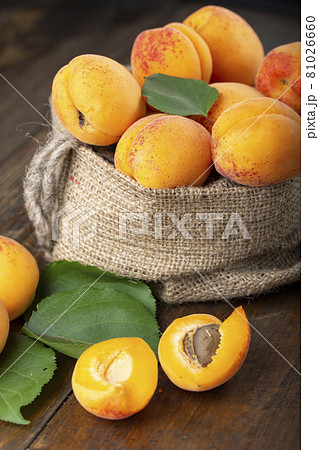Ripe apricots and apricot leaves on the wooden background. Ripe apricots and apricot leaves on the wooden background. 81026660