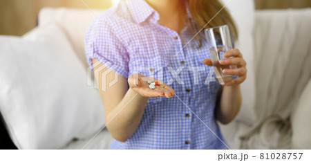 Close-up woman holding pills time to take medications, cure for headache. Medicine concept during self isolation and Coronavirus pandemic 81028757