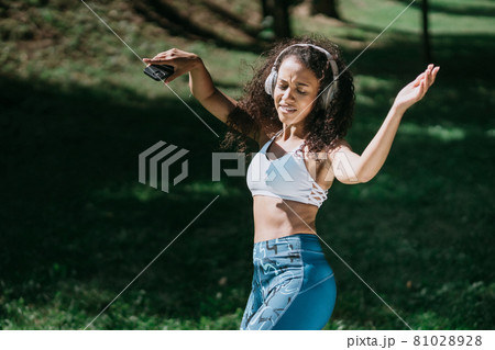 beautiful athletic woman in headphones dancing outdoors . 81028928