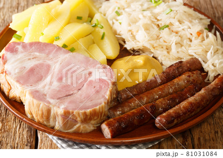 German Kassler pork neck with Sauerkraut potatoes and mustard on wooden table closeup in the plate. Horizontal German Kassler pork neck with Sauerkraut potatoes and mustard on wooden table closeup in the plate. Horizontal 81031084