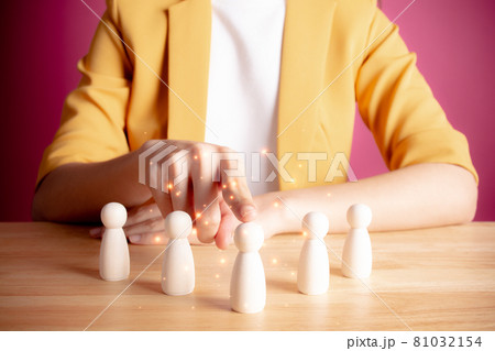 HR or human resource management concept. Young woman in yellow suite choice of an employee leader from the crowd. businesswoman holds an employee in her hand. Pink background. 81032154