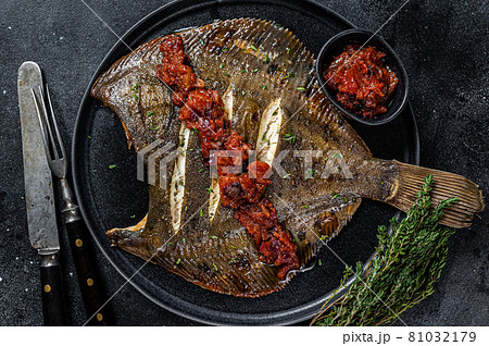 Roasted Flatfish or Flounder in a tomato sauce. Black background. Top view Roasted Flatfish or Flounder in a tomato sauce. Black background. Top view 81032179