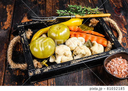 Homemade marinated and pickles vegetables preserve on a wooden tray. Dark wooden background. Top view 81032185