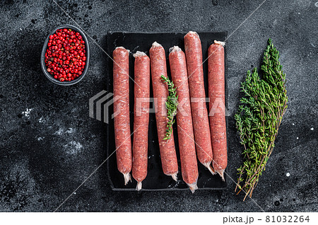 Fresh Raw butchers sausages in skins with thyme on marble board. Black background. Top view Fresh Raw butchers sausages in skins with thyme on marble board. Black background. Top view 81032264