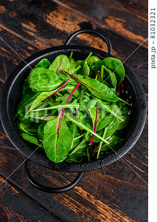 Fresh raw mixed greens, spinach, swiss chard and arugula. Dark wooden background. Top view 81032321