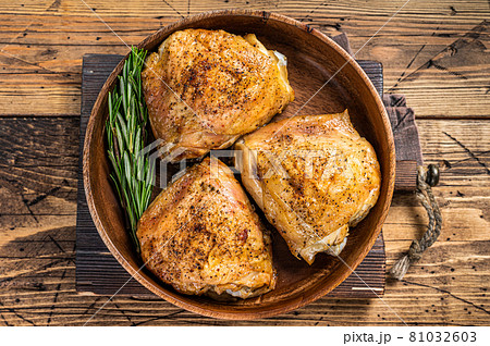 Roasted chicken thighs in a wooden plate with rosemary and herbs. wooden background. Top View Roasted chicken thighs in a wooden plate with rosemary and herbs. wooden background. Top View 81032603