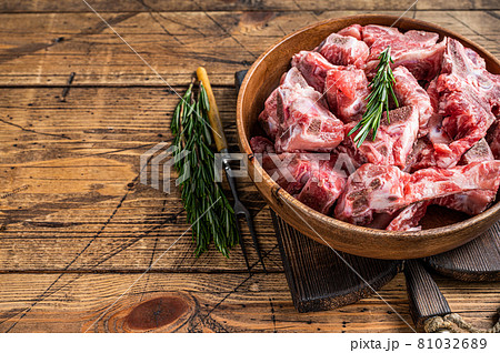 Fresh Raw meat on the bone diced for goulash in a wooden plate. Wooden background. Top View. Copy space Fresh Raw meat on the bone diced for goulash in a wooden plate. Wooden background. Top View. Copy space 81032689