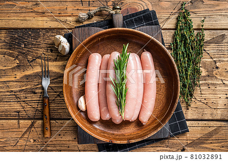 Poultry raw sausages in a wooden palte with herbs. wooden background. Top view Poultry raw sausages in a wooden palte with herbs. wooden background. Top view 81032891