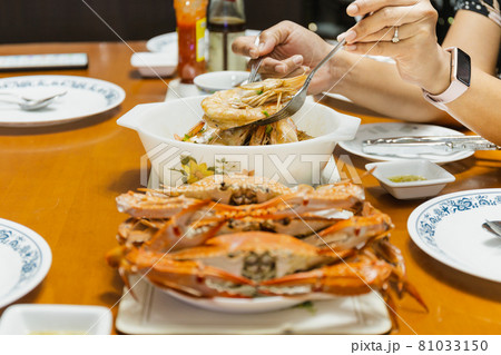 Asian woman hand holding shrimp with spoon and fork at dinner table. indoor Asian woman hand holding shrimp with spoon and fork at dinner table. indoor 81033150