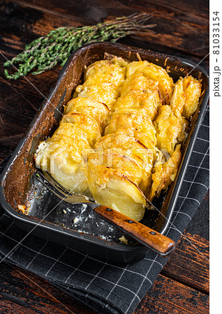 Potato casserole Gratin Dauphinois in a baking dish. Dark wooden background. Top View 81033154