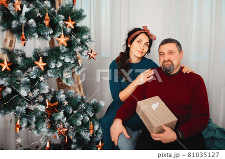 Adult family sitting at home near christmas tree Adult family sitting at home near christmas tree 81035127