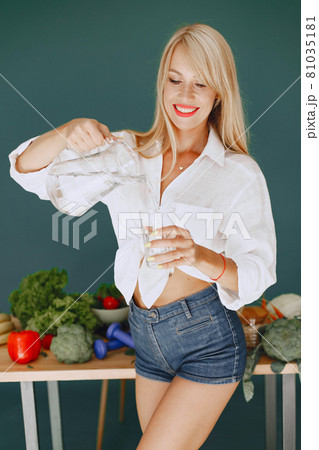 Beautiful and sporty girl in a kitchen with a vegetables 81035181