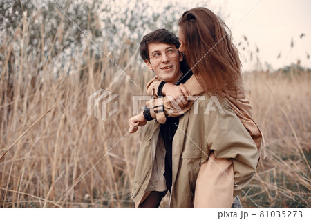 Beautiful couple spend time in a autumn field Beautiful couple spend time in a autumn field 81035273