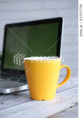 yellow color coffee mug and laptop a on table  81035746