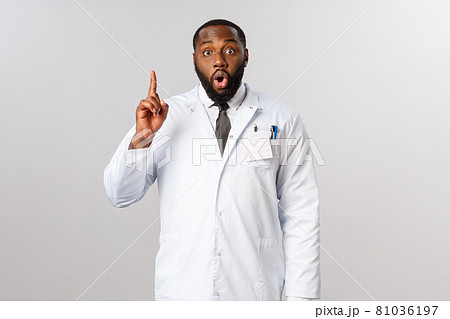 Covid19, healthcare and clinic concept. African american male doctor, physician have great idea, raise finger up eureka sign, gasping, saying his suggestion, explain plan or usage of medical masks 81036197