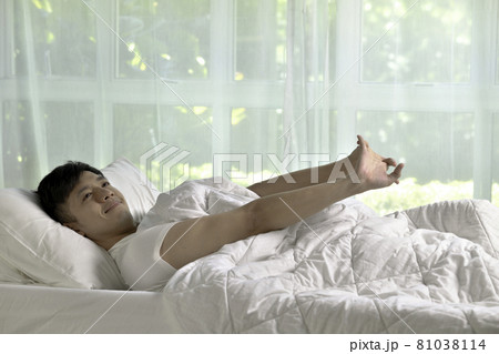 Asian man stretching in bed after wake up in the morning Asian man stretching in bed after wake up in the morning 81038114