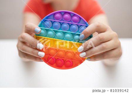 Rainbow sensory fidget isolated in the hand on white background. New trendy silicone toy. Rainbow sensory fidget isolated in the hand on white background. New trendy silicone toy. 81039142