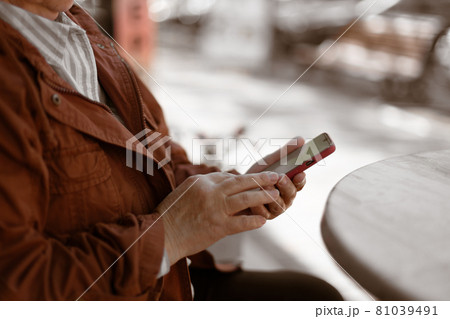 Cropped shot of woman using her mobile phone, reading messages on mobile phone in a city cafe 81039491