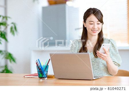 キッチンの前でテレワークする若いスマホを持ったビジネスウーマン 81040271