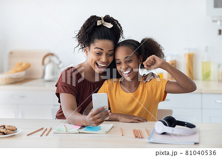Emotional mother and daughter taking selfie together 81040536